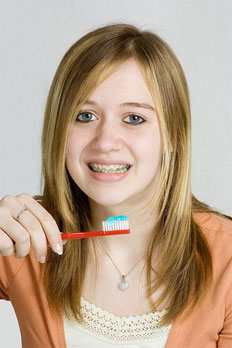 stock photo of teen girl with braces brushing her teeth